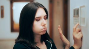 Uncomfortable Woman Adjusting Thermostat